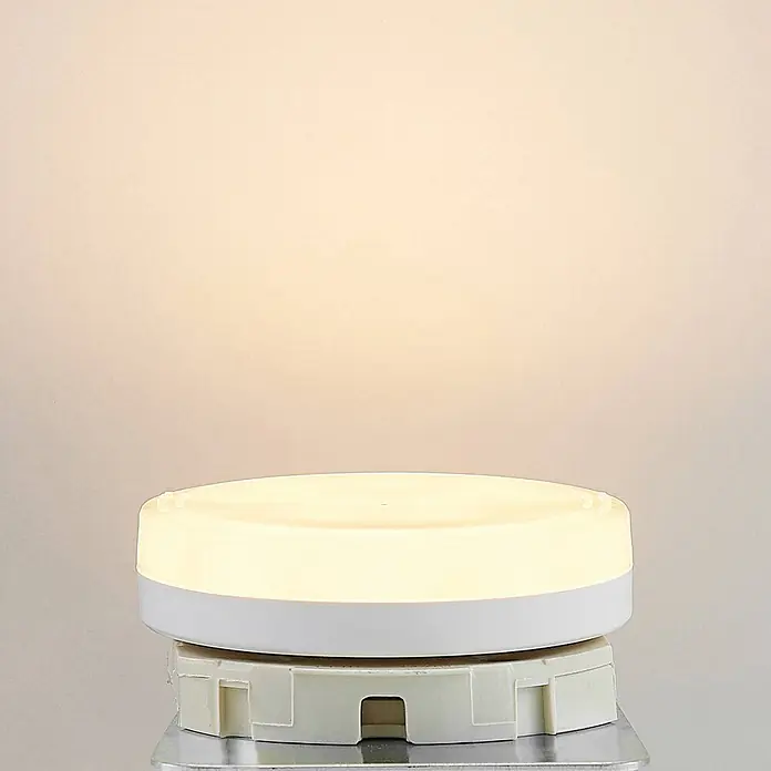 Arcchio Leuchtmittel -  - Beleuchtete weiße runde LED-Leuchte mit warmem Licht auf einem hellen Montagesockel.