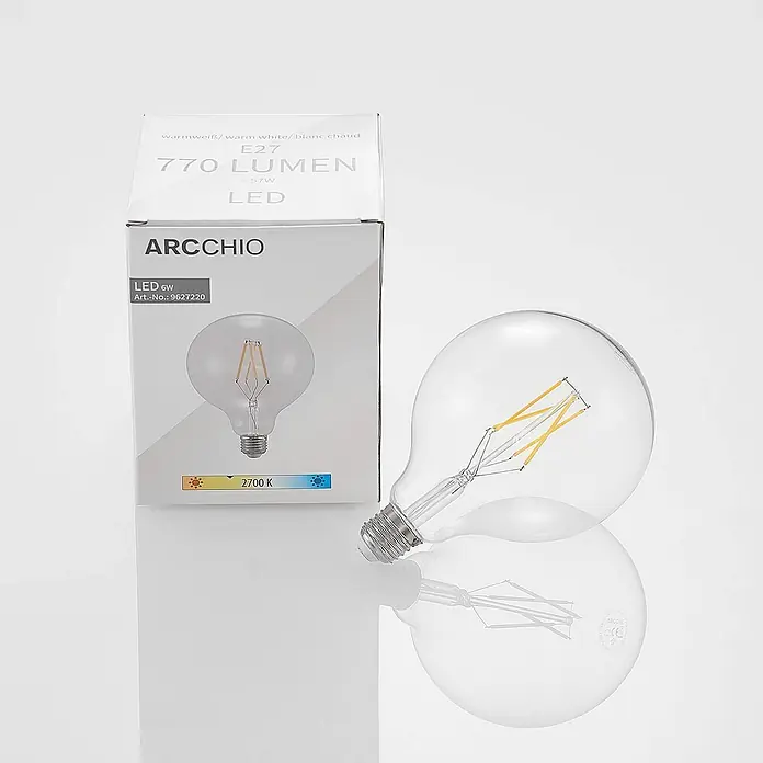 Arcchio Leuchtmittel -  - Eine klare ARCCHIO LED-Glühbirne aus Glas mit sichtbaren gelben Filamenten, neben der weißen Verpackung mit 6W, 770 Lumen, E27, 2700K.