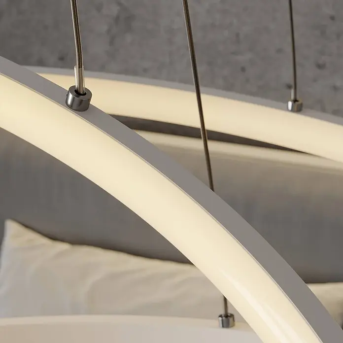 Lucande LED Pendelleuchte modern dimmbar, Esstisch Hängelampe Metall, -  - Nahaufnahme einer modernen, gebogenen, matten weißen LED-Pendelleuchte, beleuchtet und an dünnen silbernen Kabeln hängend.