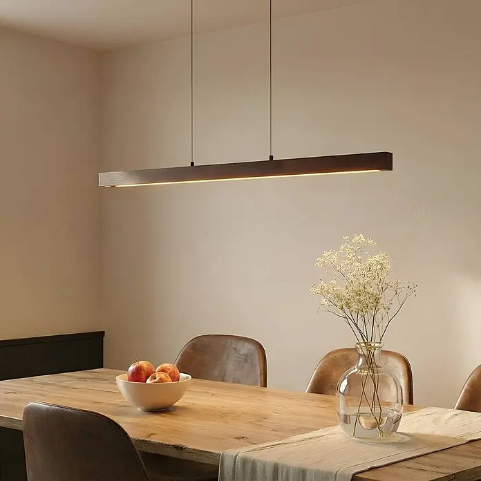 Lucande LED Pendelleuchte in walnuss, schwarz, dimmbar Hängelampe -  - Lineare LED-Pendelleuchte mit dunklem Holzgehäuse, beleuchtet über einem Esstisch.