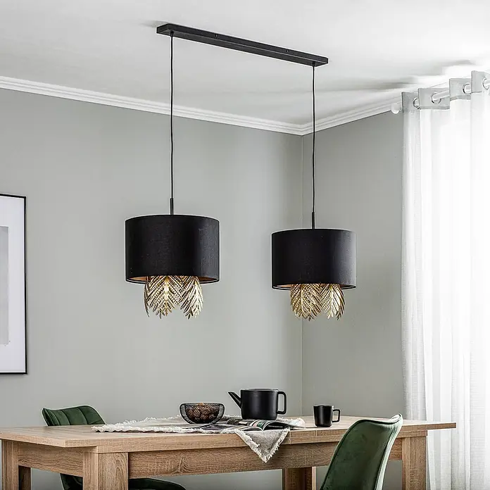 Lucande Pendelleuchte in schwarz, gold, Hängelampe -  - Doppel-Pendelleuchte mit schwarzen Stoffschirmen und goldenen Blattdetails, beleuchtet einen Esstisch.