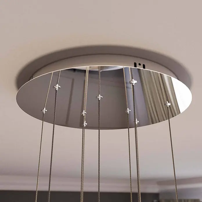 Lucande LED Pendelleuchte in transparent, chrom, Hängelampe -  - Runde, graue Deckenhalterung für eine Pendelleuchte mit mehreren Kabeln, gesichert durch silberne Klemmen.