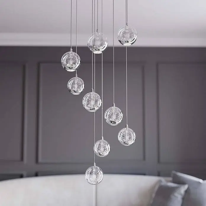 Lucande LED Pendelleuchte in transparent, chrom, Hängelampe -  - Ein mehrflammiger Pendelleuchter mit neun klaren, blasenbesetzten Glaskugeln und Chromakzenten, in unterschiedlichen Längen in einem modernen Raum hängend.