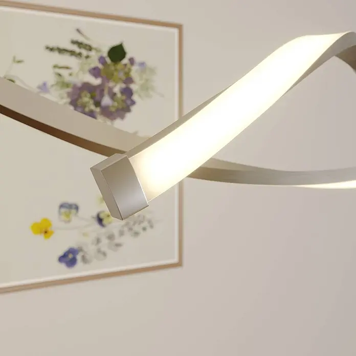 Lindby LED Pendelleuchte in nickel satiniert, weiß, Hängelampe -  - Eine moderne, geschwungene Metallleuchte mit integriertem LED-Streifen beleuchtet eine Wand mit einem gerahmten Bild.