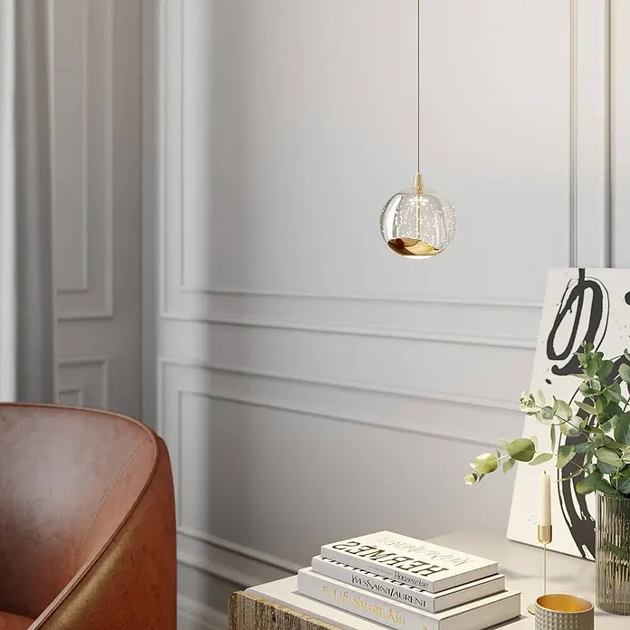Lucande LED Pendelleuchte in transparent, gold, Hängelampe -  - Eine beleuchtete Pendelleuchte aus klarem Glas mit goldenem Boden hängt von der Decke und zeigt ihr elegantes Design in einem modernen Raum.