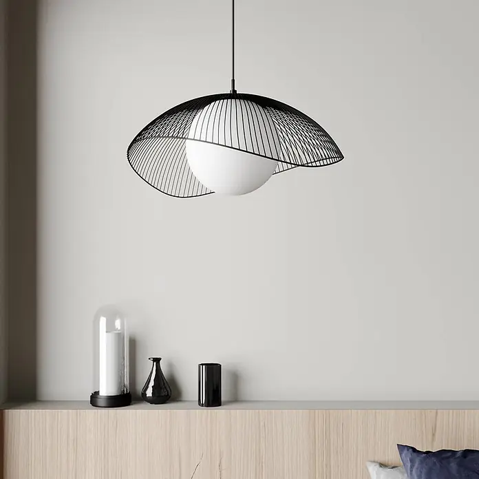 Lindby Pendelleuchte in schwarz, weiß, Hängelampe -  - Schwarze Draht-Pendelleuchte mit weißem Kugel-Diffusor, über einem Bettkopfteil hängend.