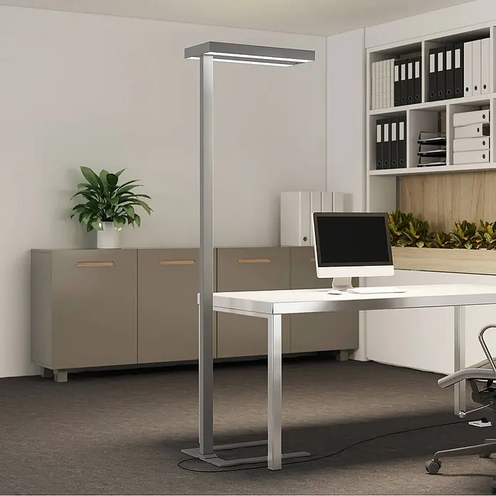 Arcchio Stehleuchte Logan Ultra - alu / grau / zink, alu / grau / zink - Moderne silbergraue LED-Stehleuchte beleuchtet einen Büroschreibtisch mit Computermonitor.
