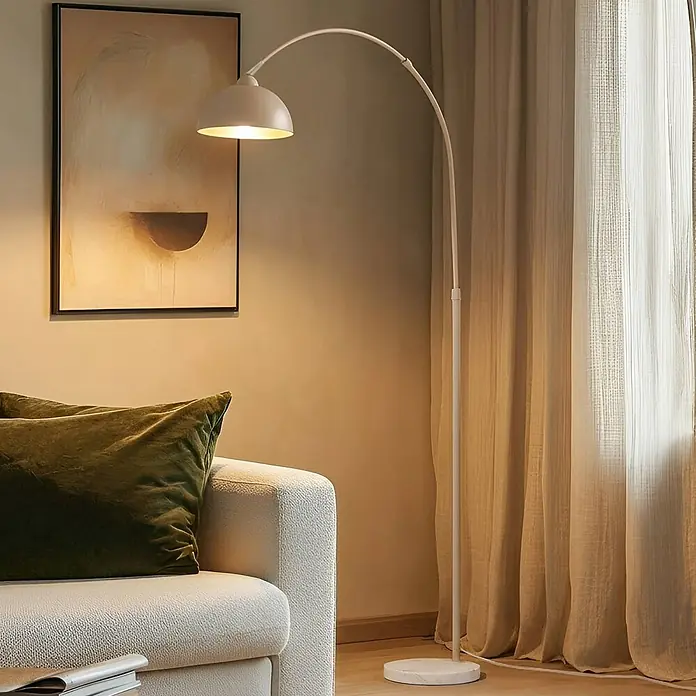 Lindby Stehlampe Wohnzimmer in beige, weiß, Stehleuchte -  - Weiße Bogen-Stehlampe mit gewölbtem Schirm und rundem Fuß, die ein modernes Wohnzimmer beleuchtet.