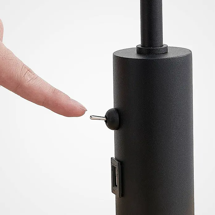 Lindby Stehlampe Wohnzimmer in schwarz matt, beige, Stehleuchte -  - Finger drückt metallischen Kippschalter an schwarzem, texturiertem Zylinder mit USB-Anschluss.