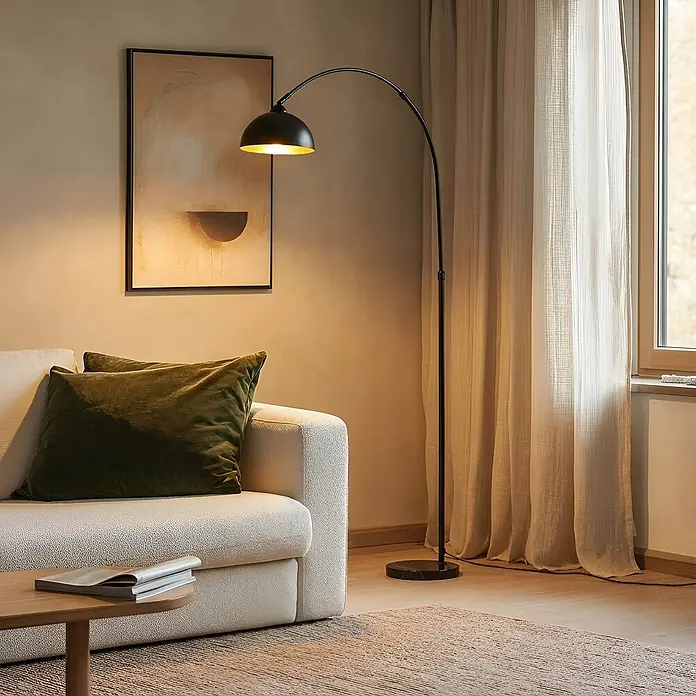 Lindby Stehlampe Wohnzimmer in schwarz, gold, Stehleuchte -  - Eine schwarze Bogenstehlampe mit goldfarbenem Schirm steht neben einem cremefarbenen Sofa in einem Wohnzimmer.