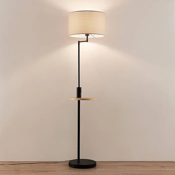 Lindby Stehlampe Wohnzimmer in schwarz matt, beige, Stehleuchte -  - Moderne Stehleuchte mit beigem Stoffschirm, schwarzem Ständer und einer Holzablage mit USB-Ladeanschluss in einem Raum.