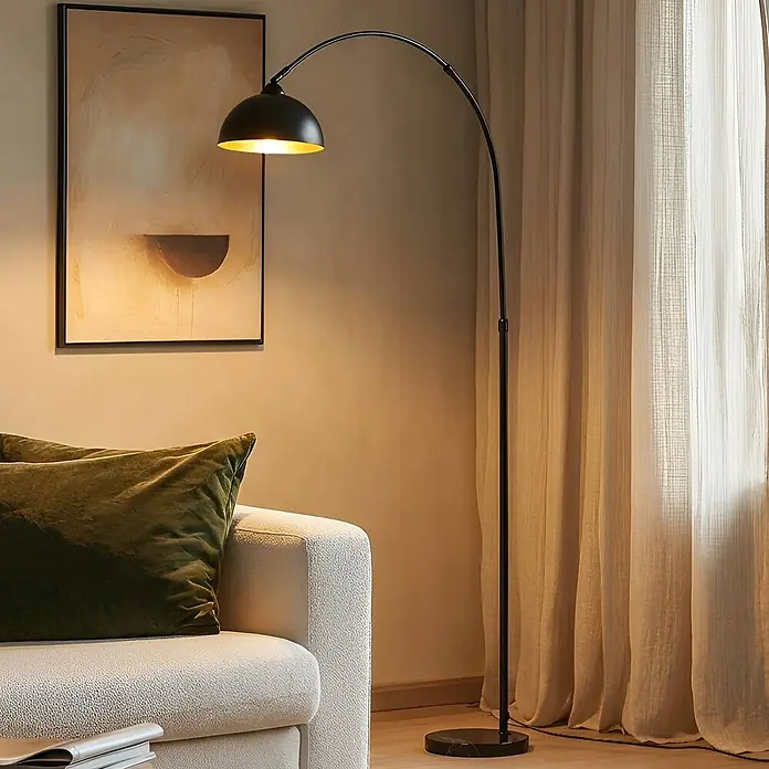 Lindby Stehlampe Wohnzimmer in schwarz, gold, Stehleuchte -  - Eine schwarze Bogenstehlampe mit goldener Innenseite beleuchtet ein Wohnzimmer neben einem hellen Sofa.