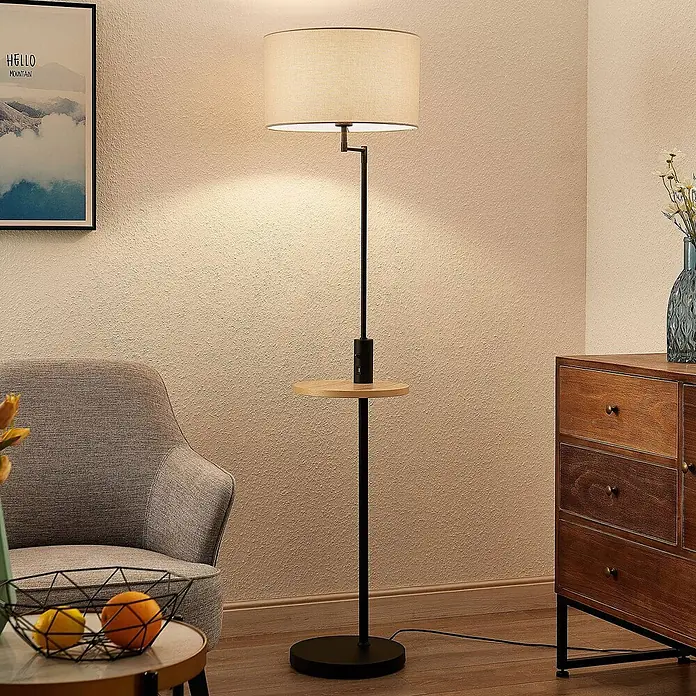 Lindby Stehlampe Wohnzimmer in schwarz matt, beige, Stehleuchte -  - Stehlampe mit beigem Stoffschirm, schwarzem Metallfuß und Holzablage mit Ladeanschluss, beleuchtet einen gemütlichen Wohnbereich.