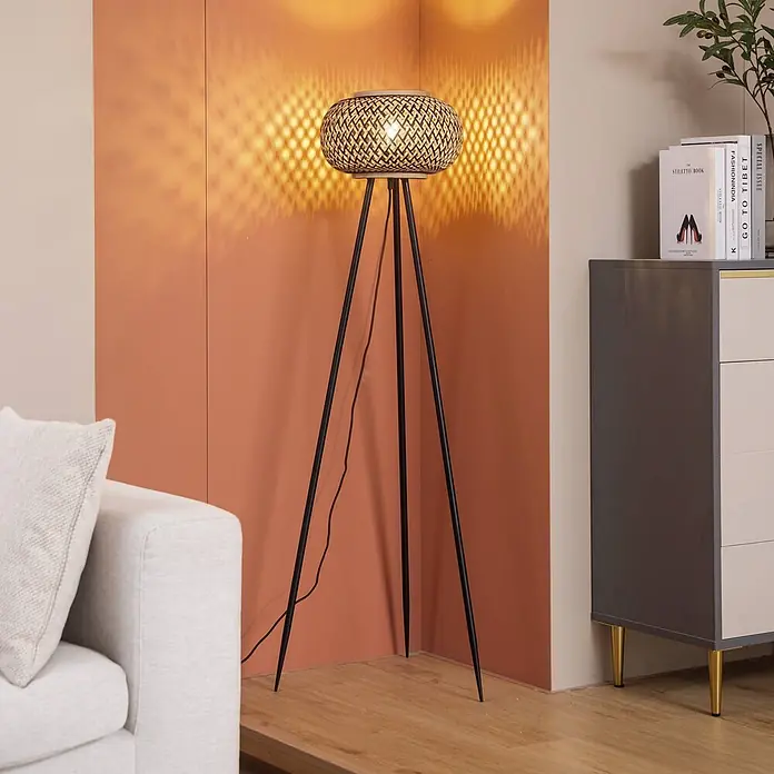 Lindby Stehlampe Wohnzimmer, Tripod in schwarz, holz, Stehleuchte -  - Bambus-Stehleuchte mit schwarzen Stativbeinen, die eine Zimmerecke beleuchtet.