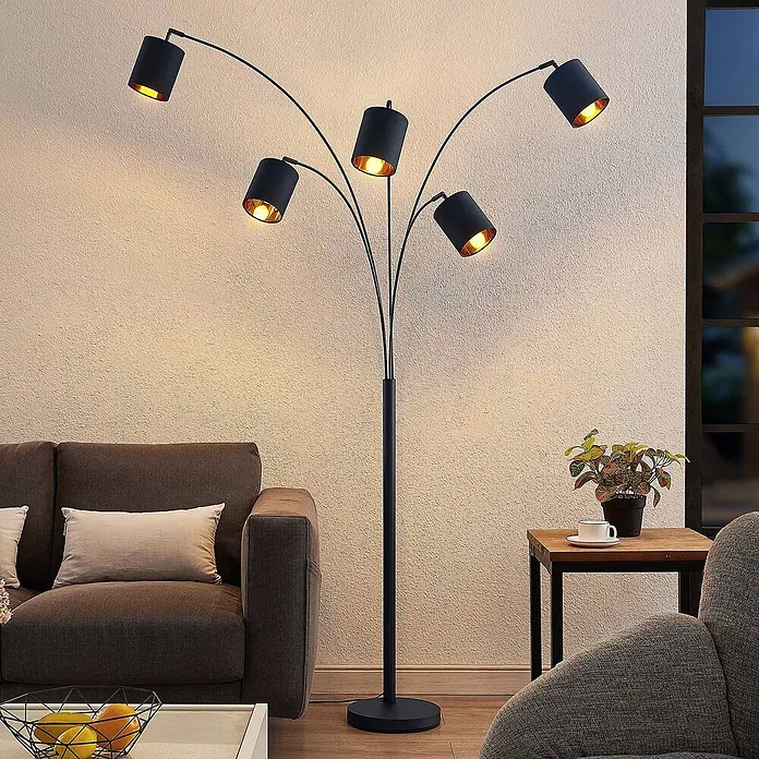 Lindby Stehlampe Wohnzimmer in schwarz, gold, Stehleuchte -  - Fünfarmige schwarze Stehleuchte mit goldenen Innenschirmen, die eine gemütliche Wohnzimmerecke beleuchtet.