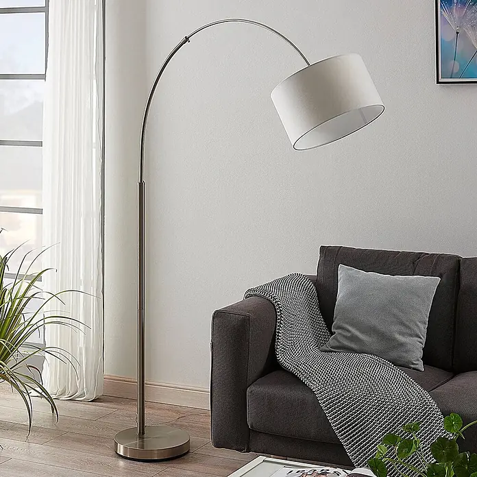 Lindby Stehlampe in nickel satiniert, weiß, Bogenlampe Wohnzimmer -  - Bogenförmige Stehleuchte aus gebürstetem Nickel mit weißem Stoffschirm, über einem Sofa platziert.