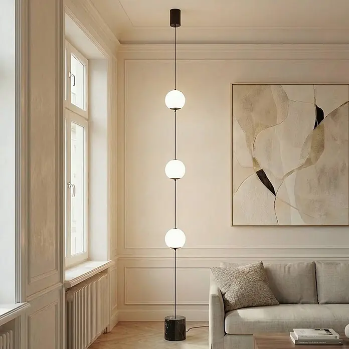 Lucande LED Stehlampe Wohnzimmer in weiß, schwarz, dimmbar Stehleuchte -  - Hohe Stehlampe mit schwarzem Stab, drei weißen Glaskugeln und schwarzem Marmorsockel, in einem Wohnzimmer.
