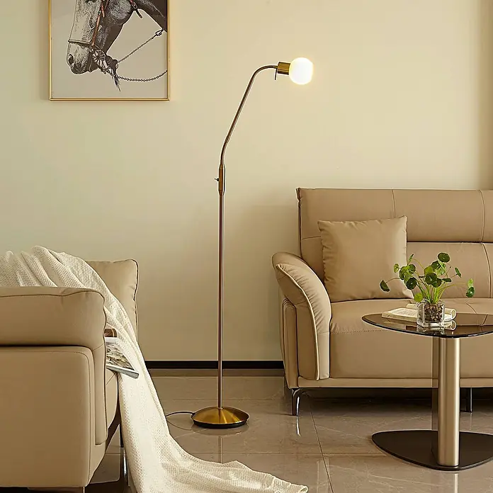 Lindby Stehlampe verstellbarer Glas Leuchtkopf, Standleuchte messing -  - Goldfarbene Stehlampe aus Metall mit einer Glühbirne, die ein modernes Wohnzimmer beleuchtet.