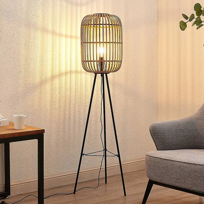 Lindby Stehlampe Wohnzimmer, Tripod in creme, schwarz, Stehleuchte -  - Stehleuchte mit Bambus-Käfigschirm und schwarzem Metall-Dreibeinstativ, beleuchtet ein Wohnzimmer.