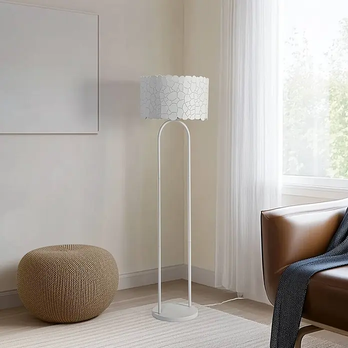 Lindby Stehleuchte Aralena - weiß / opal, weiß / opal, E27 - Weiße Stehlampe mit dekorativem, gewelltem Lampenschirm, die eine gemütliche Wohnzimmerszene mit braunem Sessel und Strickhocker beleuchtet.