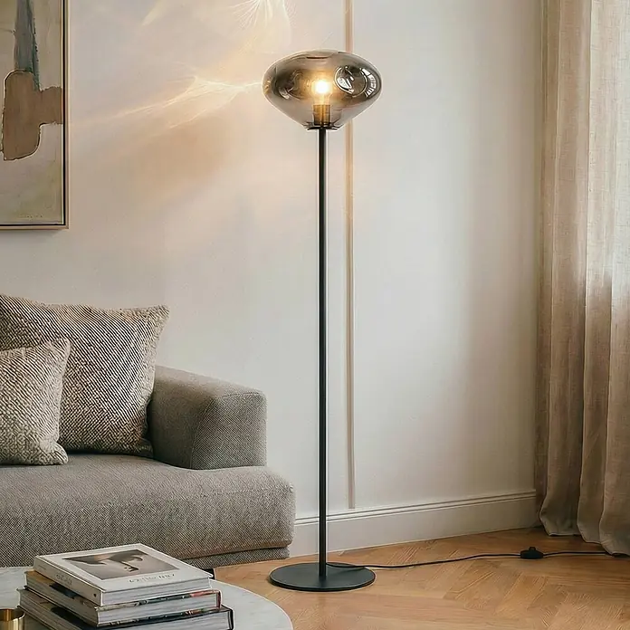 Lindby Stehlampe Wohnzimmer in rauchgrau, schwarz, Stehleuchte -  - Moderne Stehleuchte mit schwarzem Metallfuß und organisch geformtem Rauchglasschirm, beleuchtet ein Wohnzimmer.