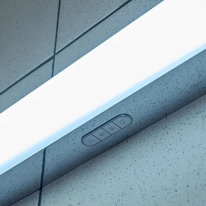 Lindby LED Wandleuchte innen in weiß, chrom, dimmbar Wandlampe -  - Lineare LED-Lichtleiste mit integrierten Berührungssteuerungen für Leistung, Helligkeit und Modus, an einer strukturierten Decke montiert.