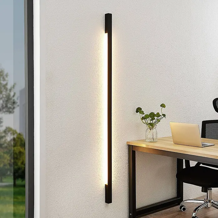 Arcchio LED Wandleuchte innen in schwarz, Wandlampe -  - Schwarze, lineare LED-Wandleuchte vertikal montiert, beleuchtet eine Wand neben einem Schreibtisch.