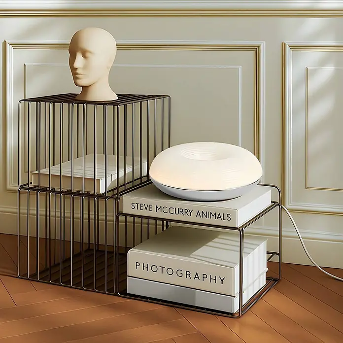 Lindby LED Wandleuchte innen in weiß, chrom, dimmbar Wandlampe -  - Zwei dunkle Metallgitterwürfelregale, gestapelt, mit Schaufensterpuppenkopf, leuchtender Lampe und Büchern.