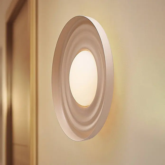 Lindby Wandleuchte Waves - creme / amber - Moderne ovale Wandleuchte in zartem Beigeton mit konzentrischen, welligen Ringen, die weiches Umgebungslicht abgibt.