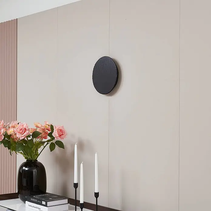 Lindby LED Wandleuchte innen in grau, schwarz, Wandlampe -  - Schwarze ovale Schiefertafel an heller Wand, umgeben von Blumen, Büchern und Kerzen, was ihre dekorative Nutzung hervorhebt.