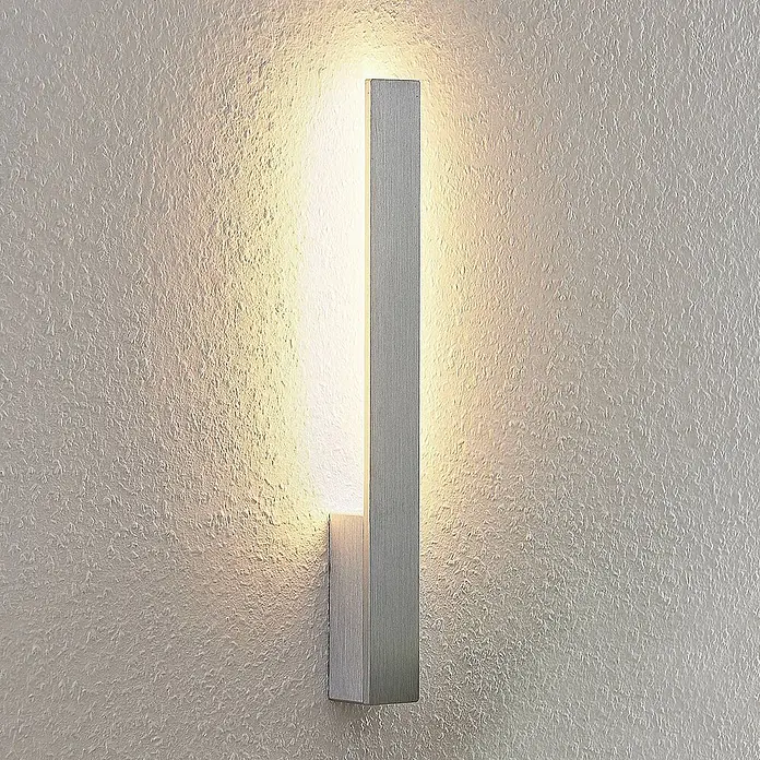 Arcchio LED Wandleuchte innen in aluminium gebürstet, Wandlampe -  - Moderne Wandleuchte aus gebürstetem Metall, an einer strukturierten Wand montiert, spendet warmes Licht nach oben und unten.