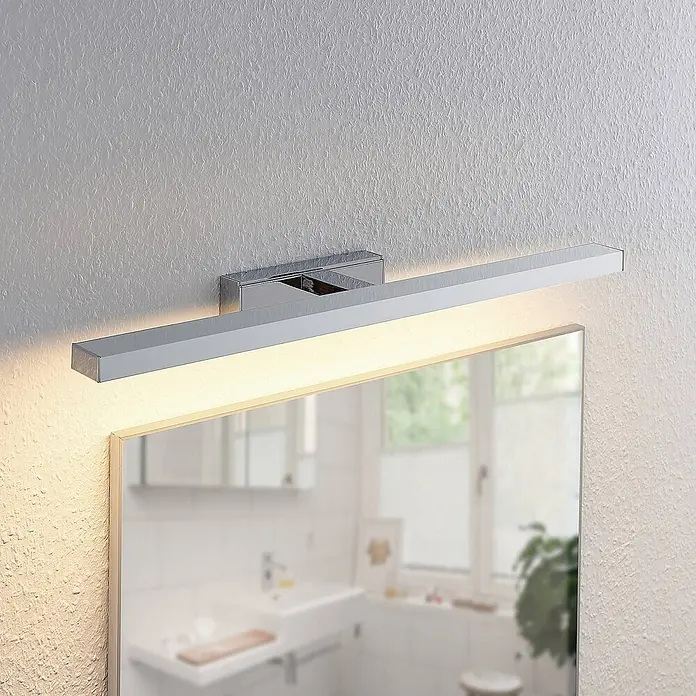 Lindby LED Wandleuchte innen in weiß, chrom, Wandlampe -  - Schlanke Chrom-LED-Spiegelleuchte horizontal über einem Badezimmerspiegel, warmes Licht nach unten strahlend.