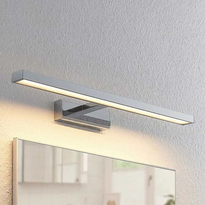 Lindby LED Wandleuchte innen in weiß, chrom, Wandlampe -  - Chromfarbene, lineare LED-Spiegelleuchte mit warmweißer Beleuchtung, über einem Spiegel an der Wand montiert.