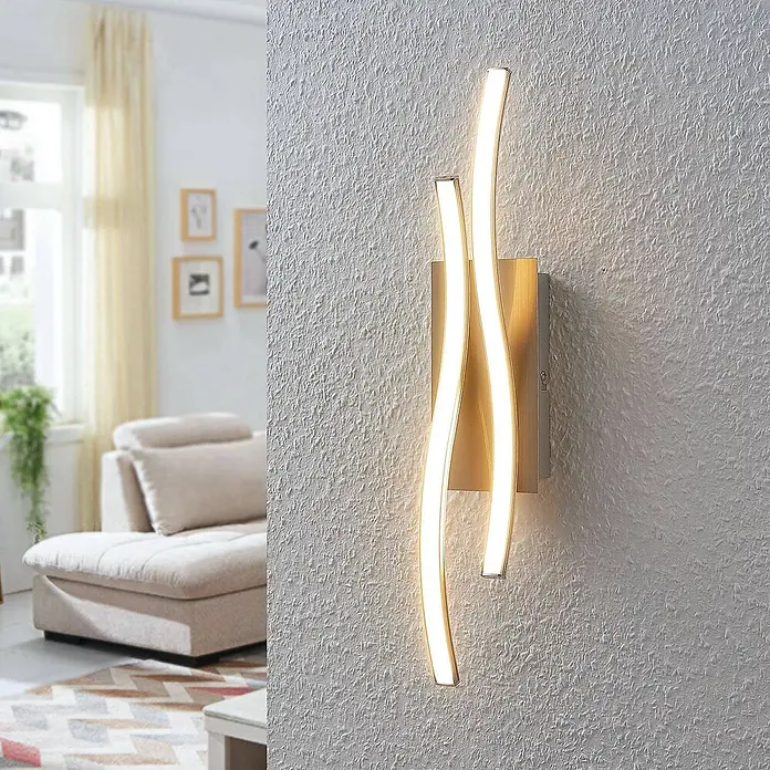Lindby Wandleuchte Safia - alu / grau / zink, alu / grau / zink - Moderne Wandleuchte mit zwei wellenförmigen, warmweißen LED-Elementen auf gebürstetem Metallsockel, die eine strukturierte Wand akzentuieren.
