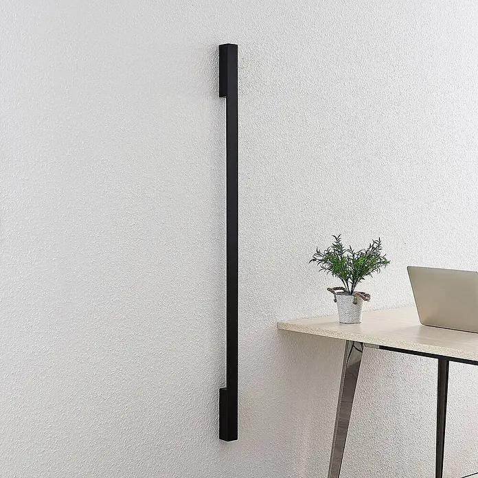 Arcchio LED Wandleuchte innen in schwarz, Wandlampe -  - Langer vertikaler schwarzer Wandbalken neben einem hellen Holzschreibtisch.