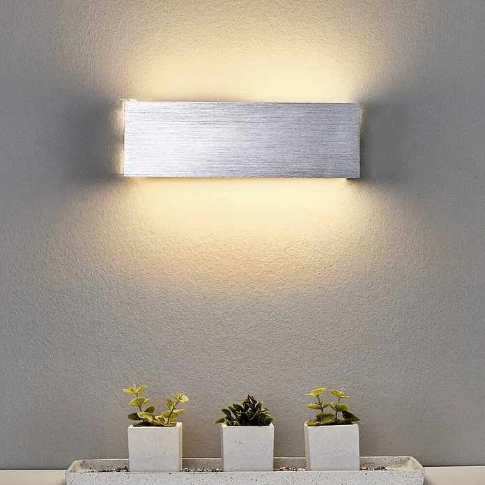 Lindby Wandleuchte Ranik - alu / grau / zink, alu / grau / zink - Rechteckige Wandlampe aus gebürstetem Silber, warmes Licht nach oben und unten werfend, mit kleinen Pflanzen darunter.