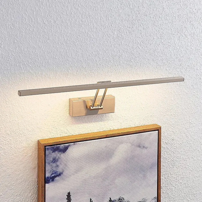 Lucande Wandleuchte Thibaud - alu / grau / zink - Bürstet Metall-LED-Bilderleuchte mit Holzsockel, die ein gerahmtes Kunstwerk beleuchtet.