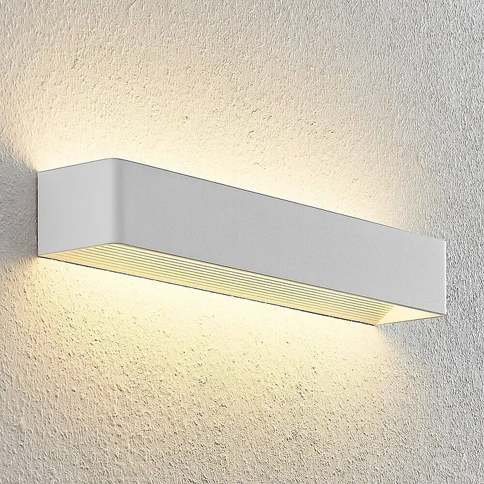 Arcchio LED Wandleuchte innen in weiß, Wandlampe -  - Weißes, rechteckiges Wandlicht an einer strukturierten Wand, das warmes Licht nach unten strahlt.