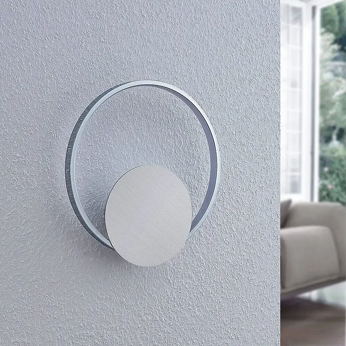 Lindby Wandlampe, Wandleuchte innen, Innenleuchte Wand, inkl. 11,2W LED -  - Moderne, silberfarbene LED-Wandleuchte mit kreisförmigem Ring und gebürsteter Metallscheibe an einer strukturierten Wand.