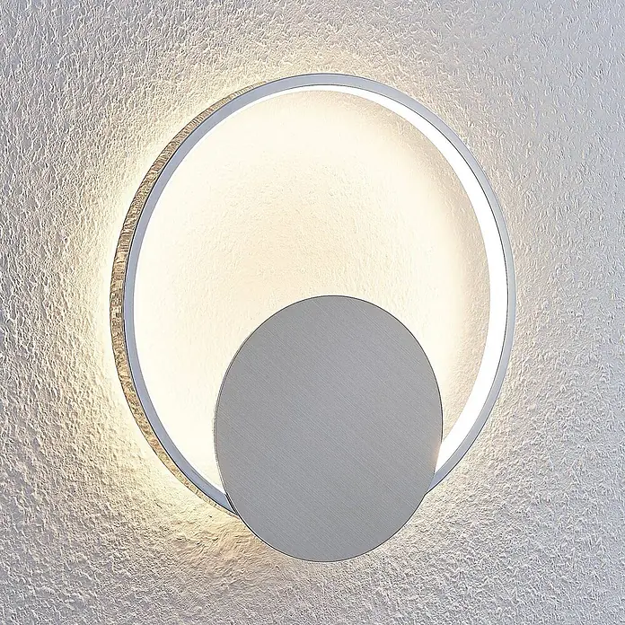 Lindby Wandlampe, Wandleuchte innen, Innenleuchte Wand, inkl. 11,2W LED -  - Moderne LED-Wandleuchte mit beleuchtetem Außenring und gebürsteter silberner Innenscheibe an strukturierter Wand.