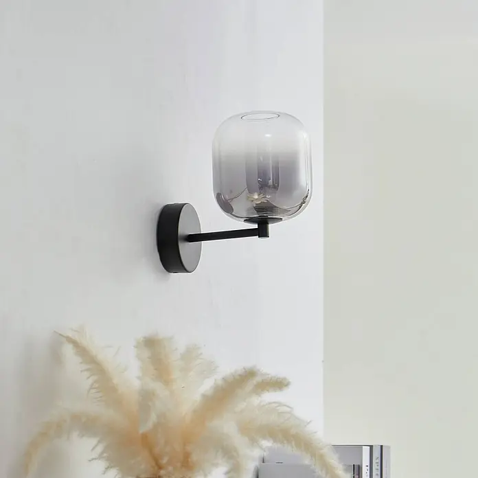 Lucande Wandleuchte Avelina - schwarz, alu / grau / zink - Moderne Wandleuchte mit schwarzem Arm und rauchgrauem Glasschirm.