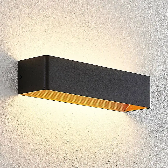 Arcchio LED Wandleuchte innen in schwarz, gold, Wandlampe -  - Schwarze, rechteckige Wandleuchte beleuchtet eine texturierte weiße Wand, innen gold gerippt.