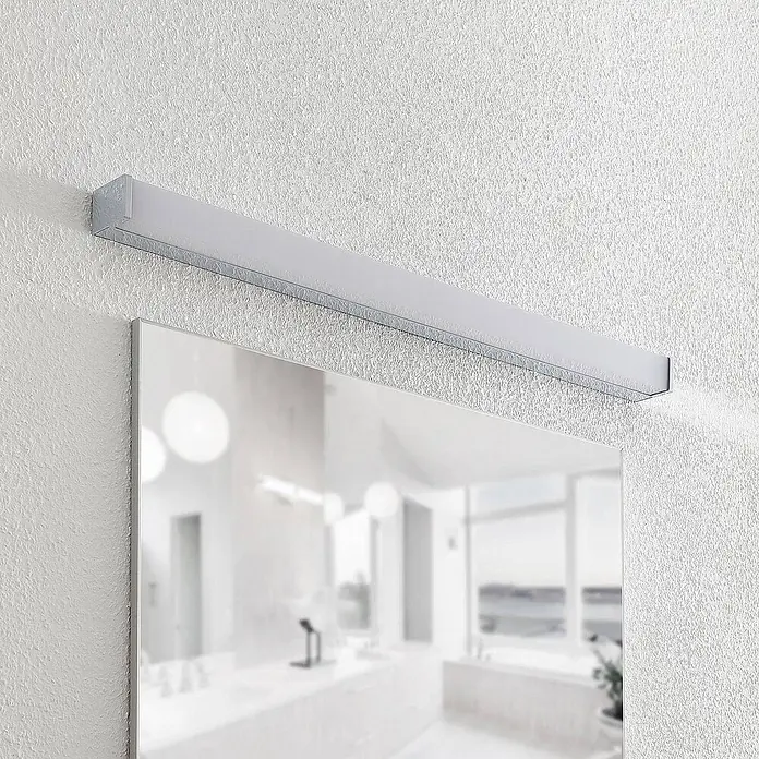 Lindby LED Wandleuchte innen in weiß, chrom, Wandlampe -  - Lineare silberne LED-Spiegelleuchte an strukturierter weißer Wand über einem Spiegel in einem modernen Badezimmer.