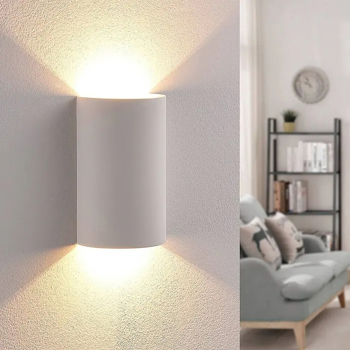 Lindby LED Wandleuchte innen in weiß, Wandlampe -  - Weiße zylindrische Wandleuchte strahlt warmes Licht nach oben und unten und beleuchtet eine strukturierte Wand im Wohnzimmer.