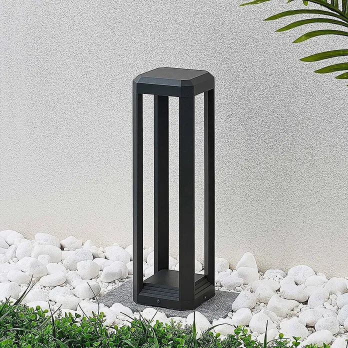 Lucande LED Wegeleuchte Sockelleuchte 50 cm, Gartenlampe, Außenlampe -  - Schwarze rechteckige Außenleuchte für Gärten, platziert zwischen weißen Kieselsteinen und Grünpflanzen.