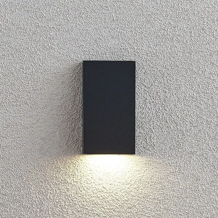 Lucande LED Wandleuchte aussen in dunkelgrau, Aussenlampe Wand -  - Schwarze, rechteckige Wandleuchte an einer strukturierten Wand, die warmes Licht nach unten abgibt.