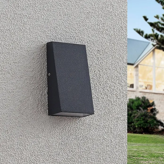 Lucande LED Wandleuchte aussen in dunkelgrau, Aussenlampe Wand -  - Dunkelgraue rechteckige Außenwandleuchte mit abgeschrägtem Design an einer strukturierten hellgrauen Außenwand.
