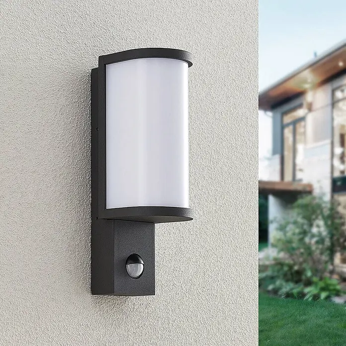 Lucande LED Wandleuchte aussen in graphit, weiß, mit Bewegungsmelder, -  - Dunkelgraue Außenwandleuchte mit mattweißem Diffusor und integriertem Bewegungsmelder, an einer strukturierten Außenwand montiert.