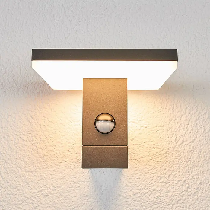 Lucande LED Wandleuchte aussen in anthrazit, weiß, mit Bewegungsmelder, -  - Moderne anthrazitfarbene Wandleuchte mit Bewegungsmelder, beleuchtet eine strukturierte Wand.