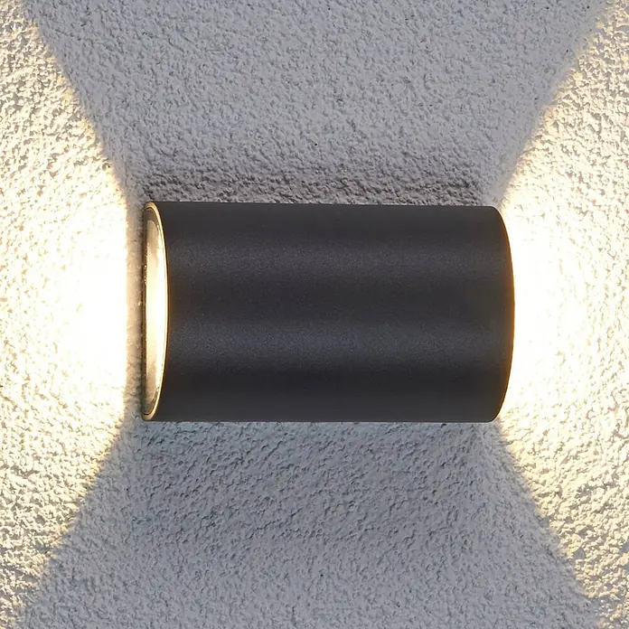 Lucande LED Wandleuchte aussen in anthrazit, transparent, Aussenlampe Wand -  - Schwarze zylindrische Außenwandleuchte, die Licht nach oben und unten auf eine strukturierte Wand wirft.
